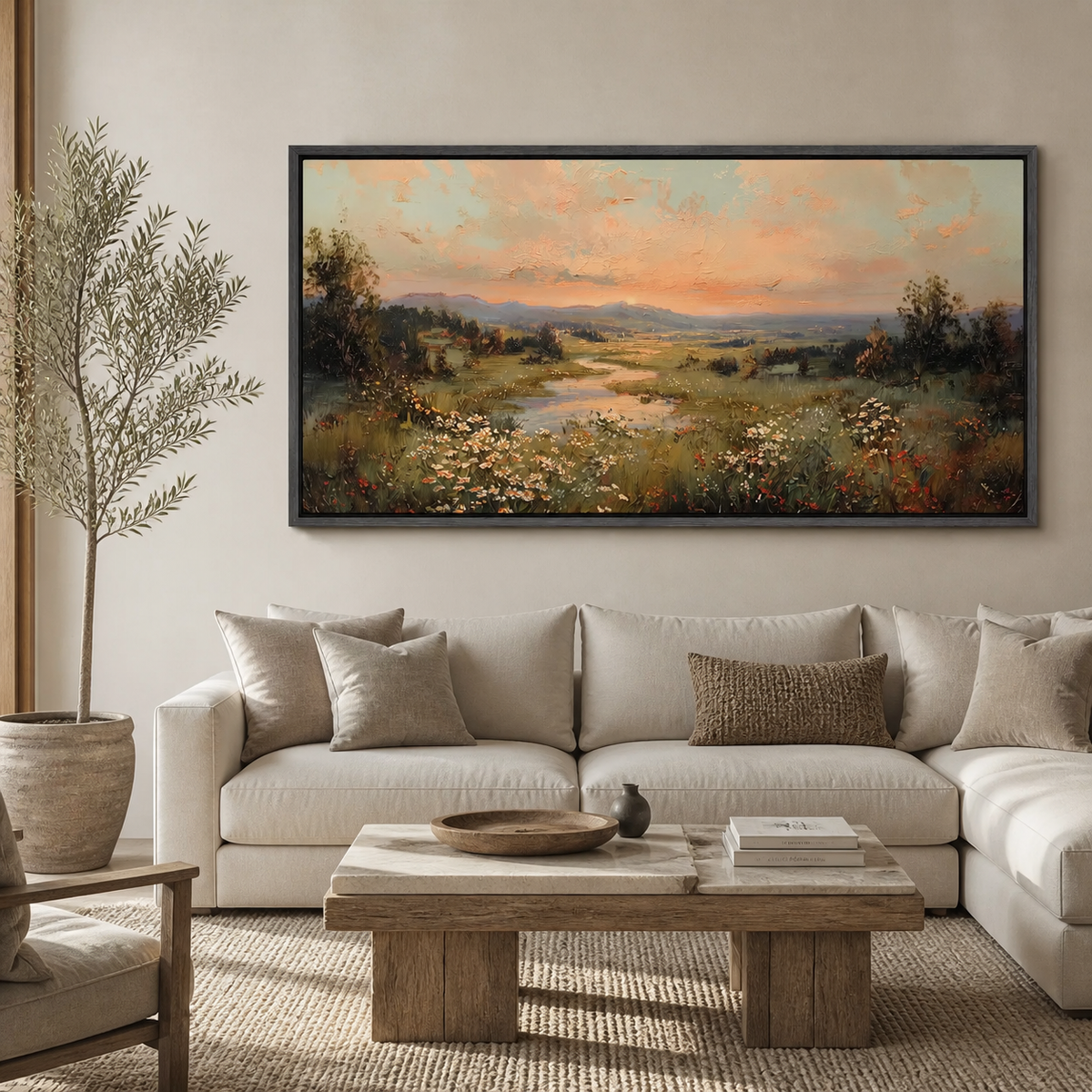 Panoramic wildflower meadow landscape wall art with a winding stream, distant hills and warm sunset sky displayed above a neutral sofa.