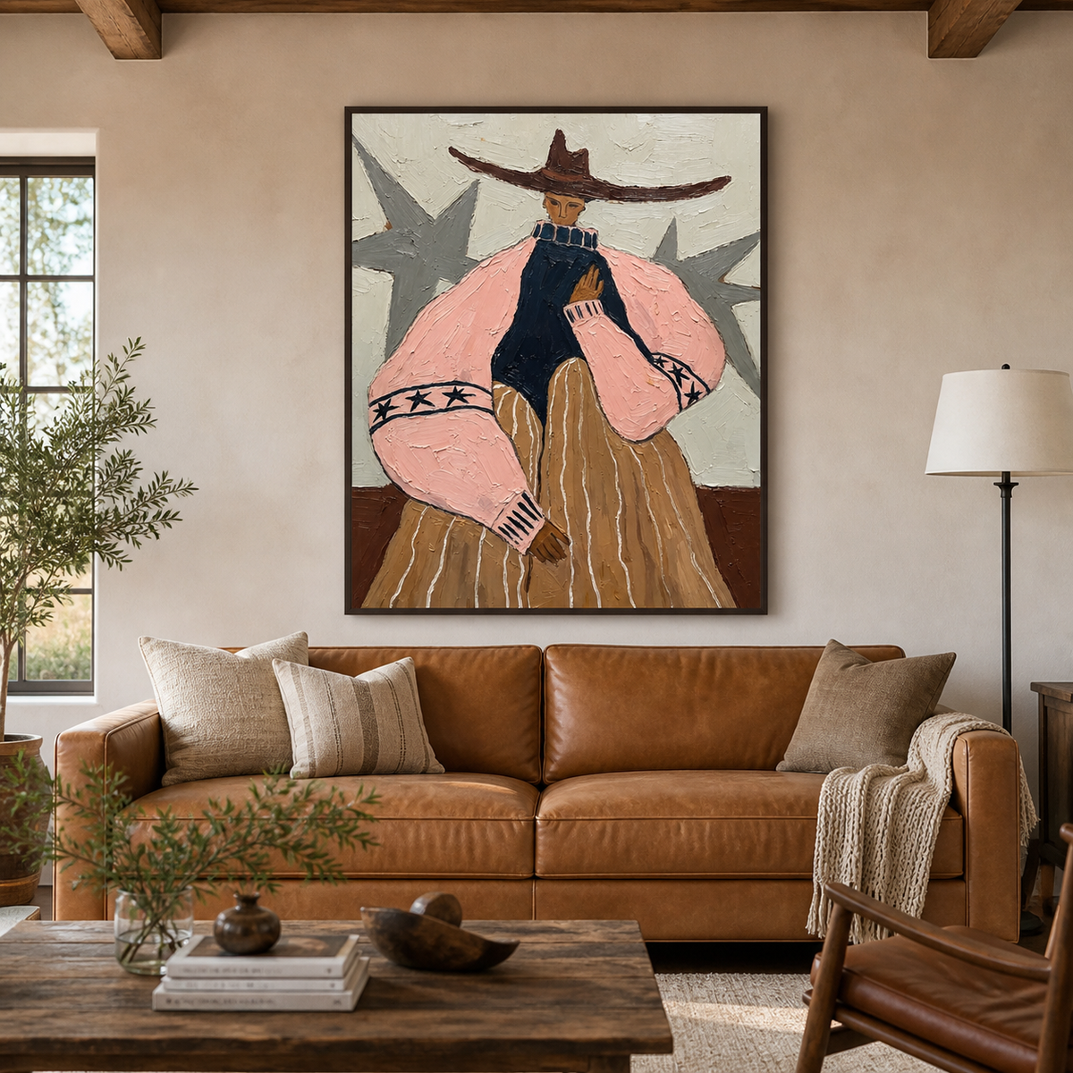 Western woman wall art with a wide brown hat, pink sleeves and ochre skirt displayed above a leather sofa.