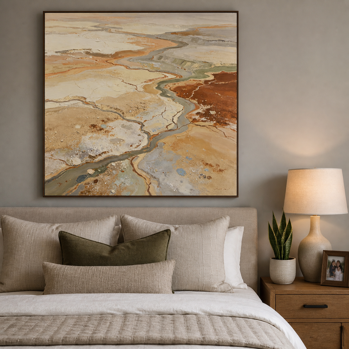Square neutral textured wall art with winding abstract river channels in beige, terracotta, gray and sage displayed above a dining table.