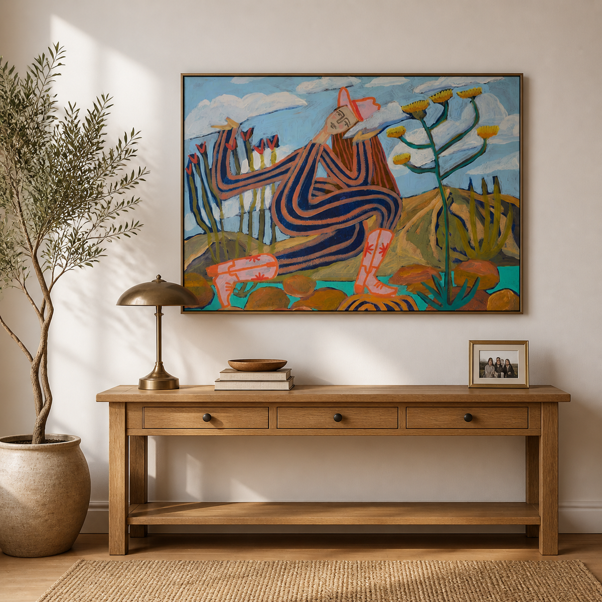 Colorful Southwestern figurative wall art with a seated striped figure, cactus plants and desert flowers above a sofa.