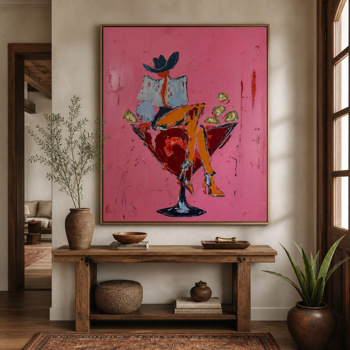 Cocktail cowgirl wall art with a hat-wearing woman seated in a red martini glass displayed above an entryway console.