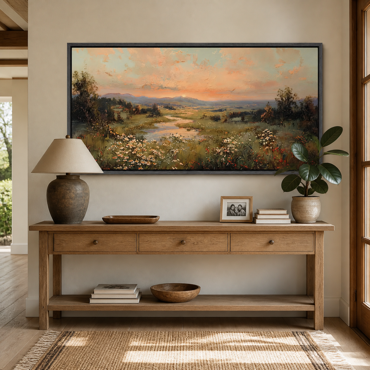 Panoramic wildflower meadow landscape wall art with a winding stream, distant hills and warm sunset sky displayed above a neutral sofa.