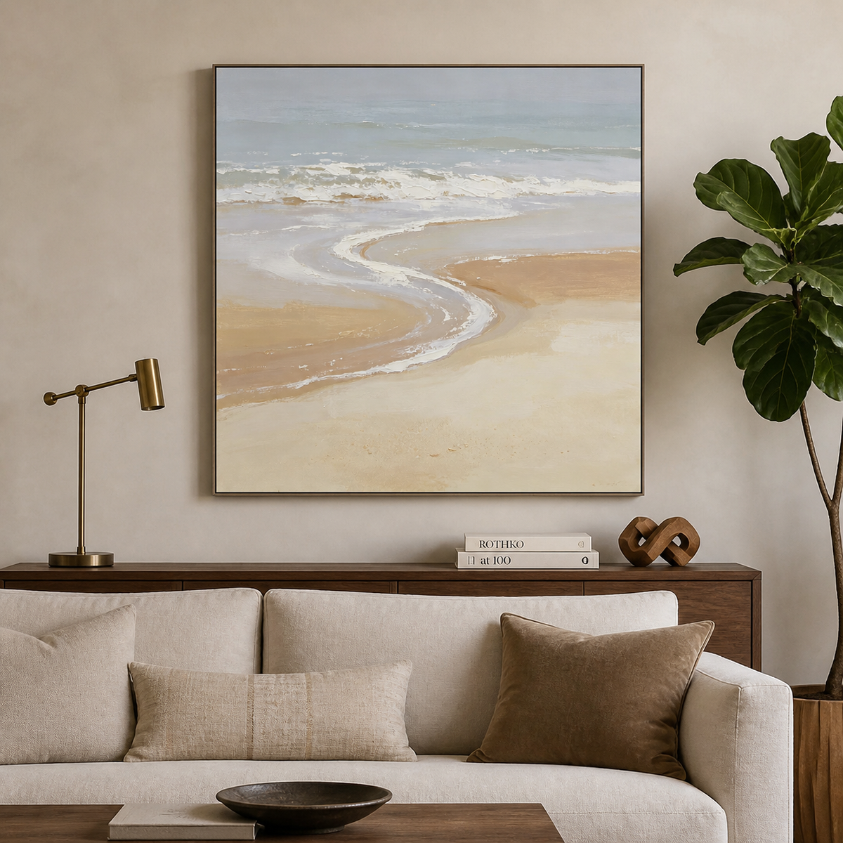 Square neutral coastal wall art with soft blue-gray ocean waves and a curved beige shoreline displayed above a wooden dining table.
