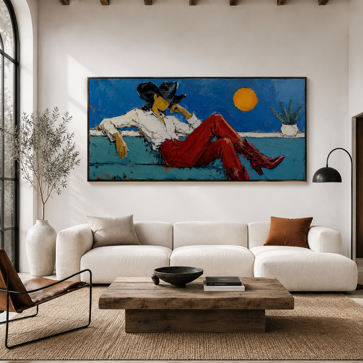 Hand-painted cowgirl wall art featuring a woman in red Western boots and black cowboy hat reclining on a teal sofa against a blue background