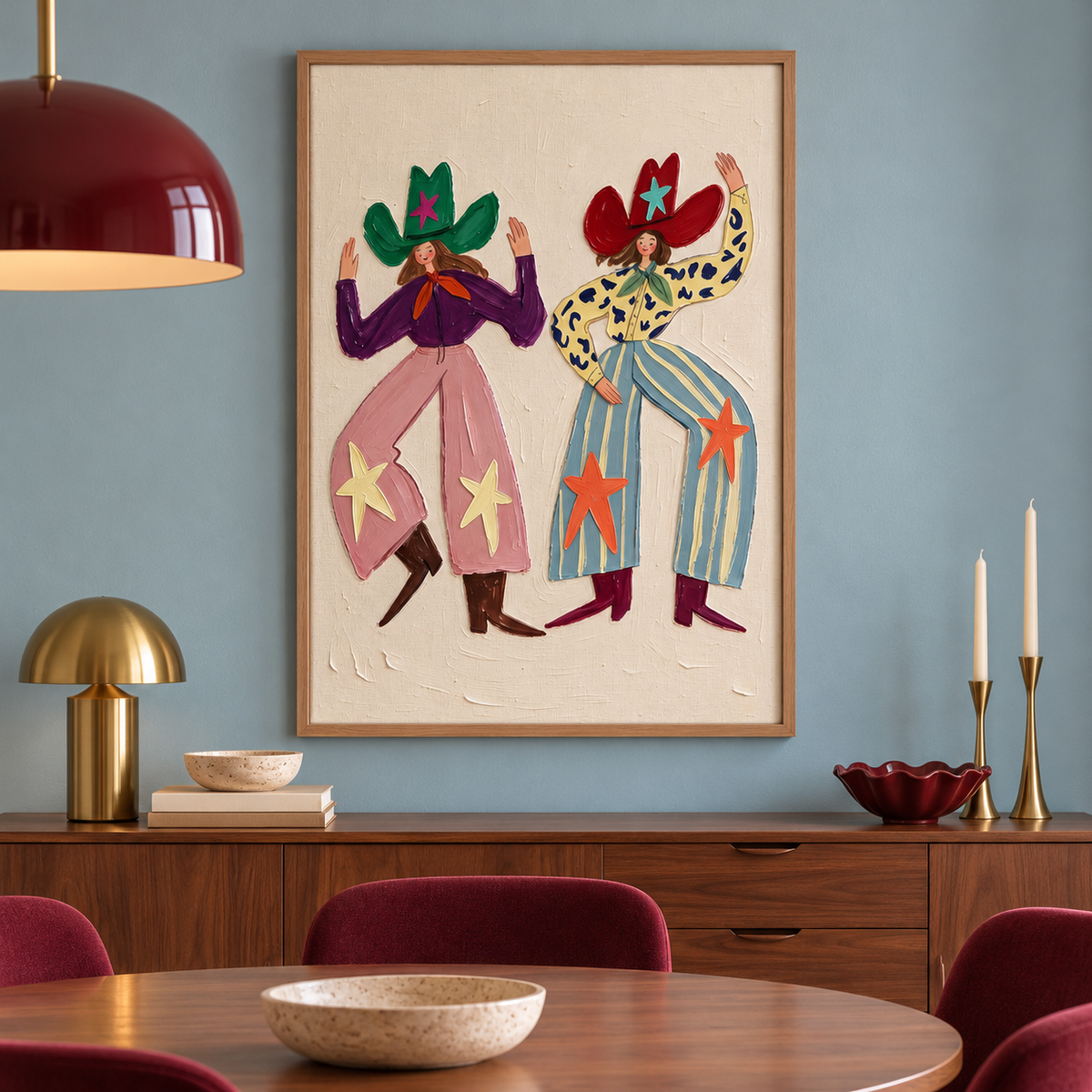 Two smiling cowgirls dancing with raised arms in oversized green and red star-decorated hats, pink and blue patterned pants and pointed boots on a cream background, shown in room setting 3.