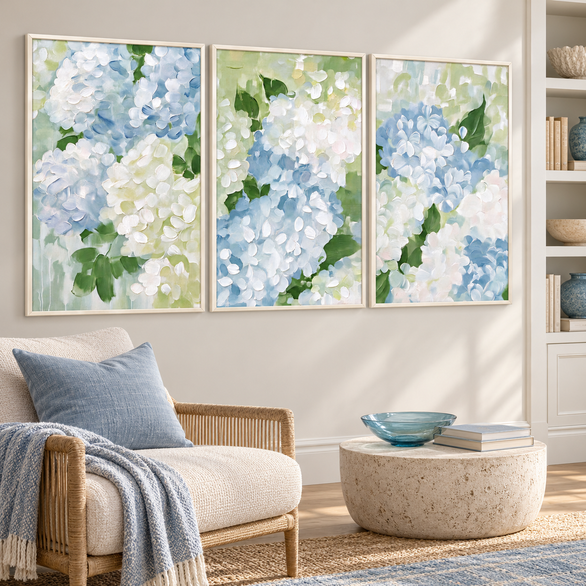 A three-panel hydrangea wall art set with close-up clusters of pale blue and white petals and green leaves spread across three separate vertical panels, shown from an angle in a reading corner.