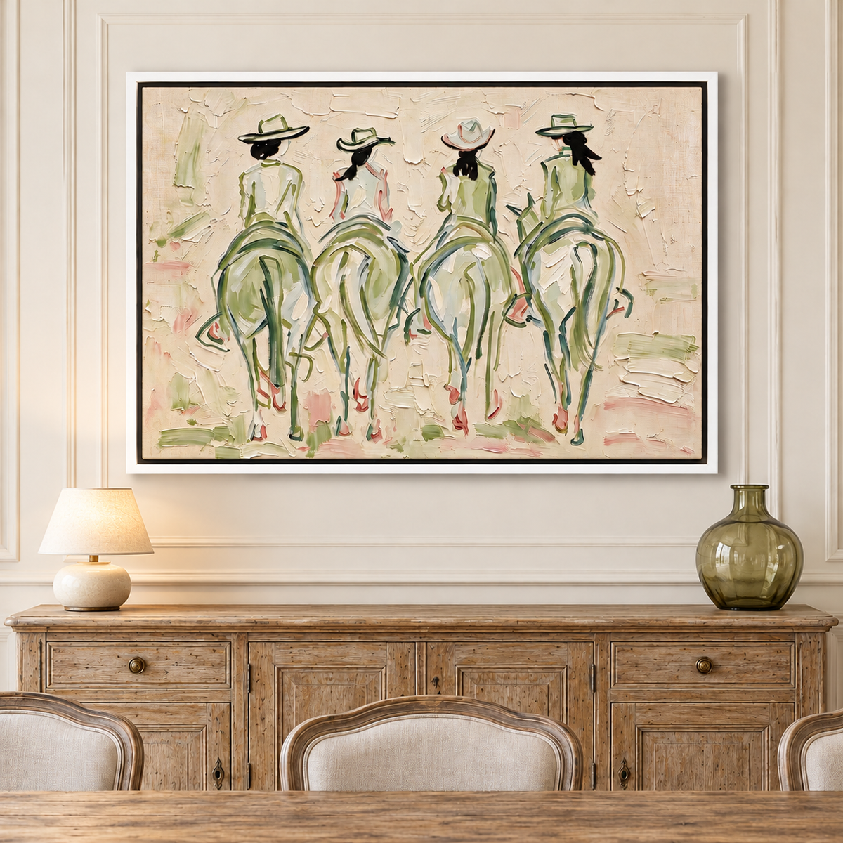 Four cowgirls on horseback seen from behind, with wide-brimmed hats and long dark ponytails, outlined in sage green and pale pink against a cream background, shown in room setting 2.