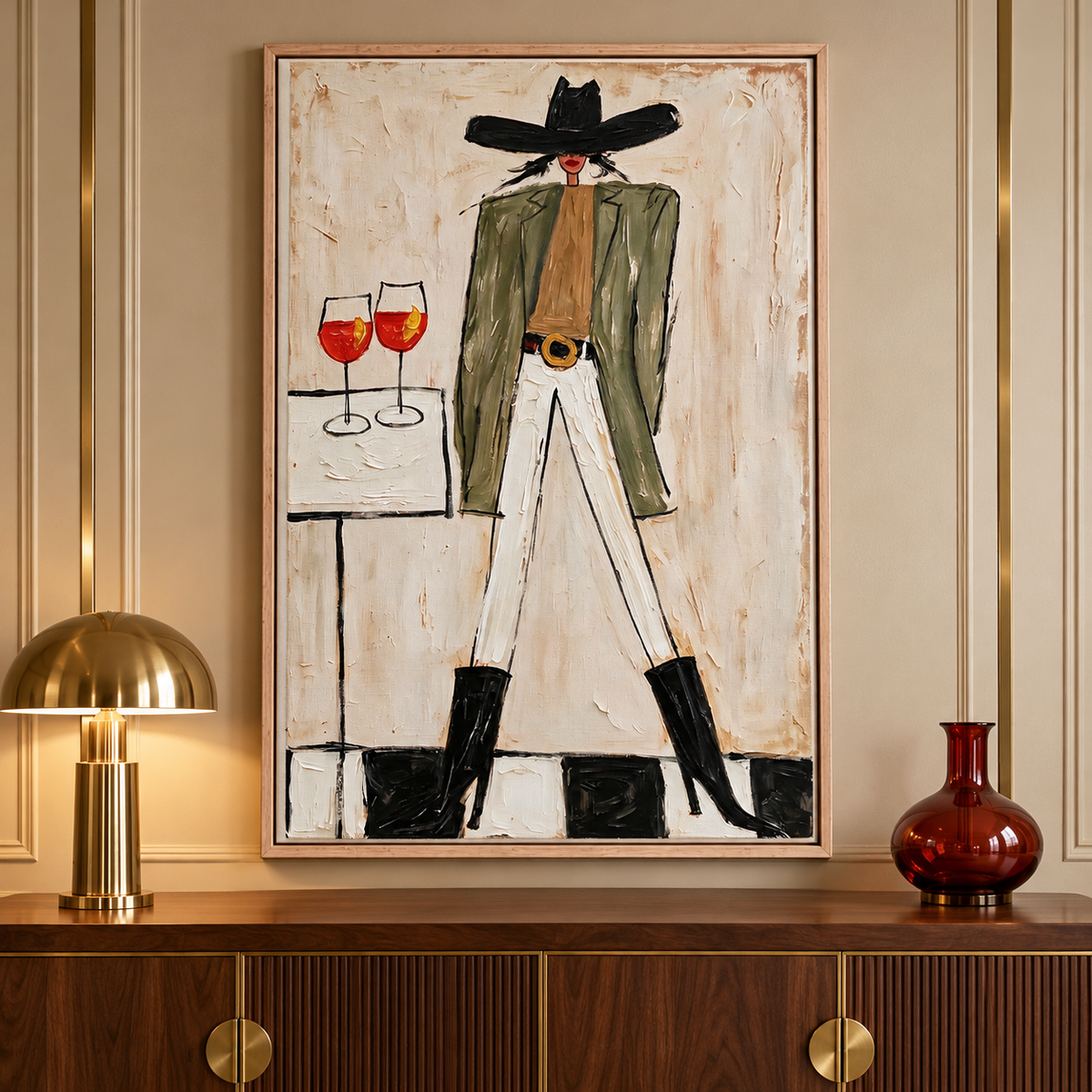 A woman in a wide black cowboy hat, olive-green jacket, white pants and black boots standing beside a small table with two orange-red drinks in stemmed glasses, shown in room setting 2.