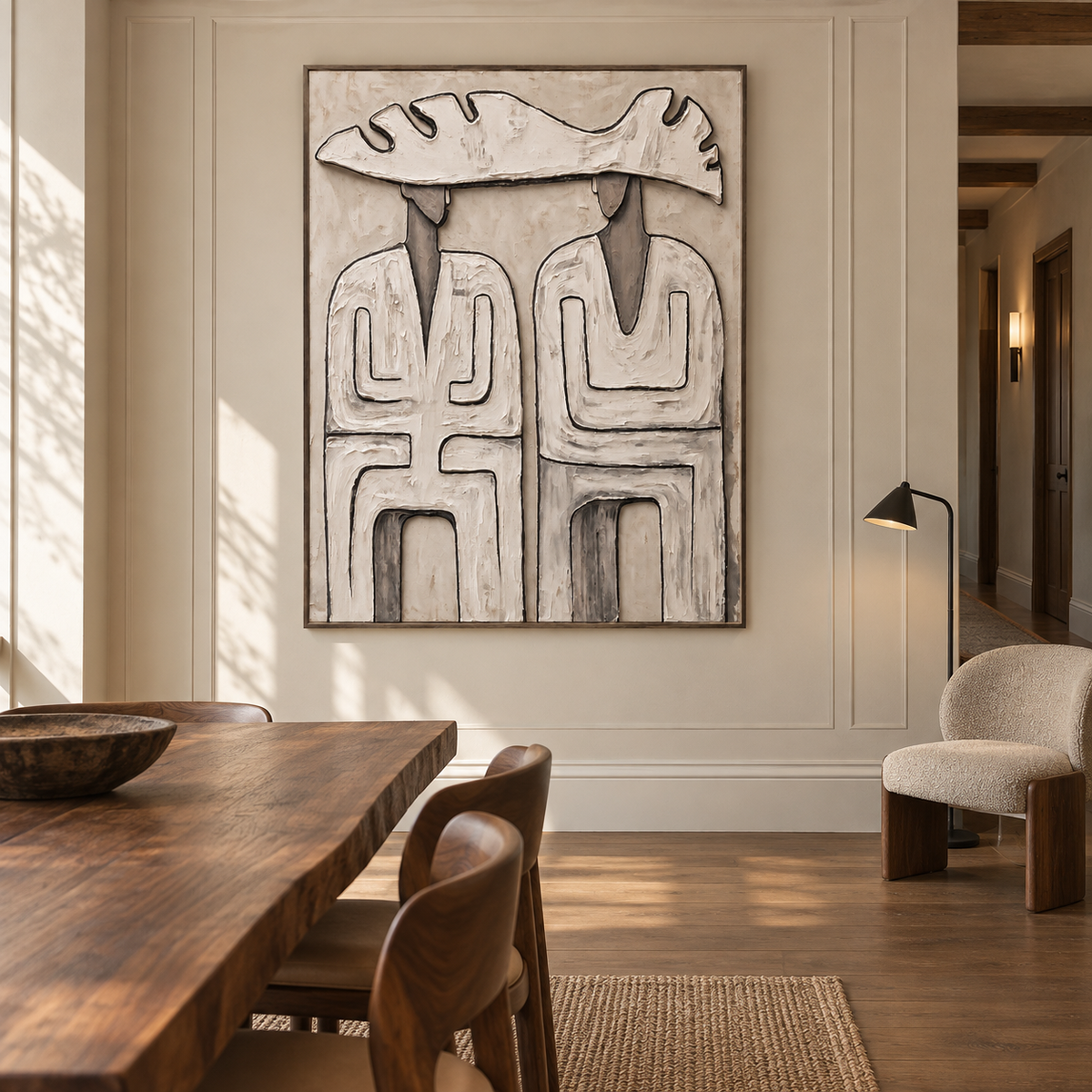 Two abstract figures beneath a single wide pale hat with dark geometric outlines on a warm neutral background, shown in a organic modern dining room.