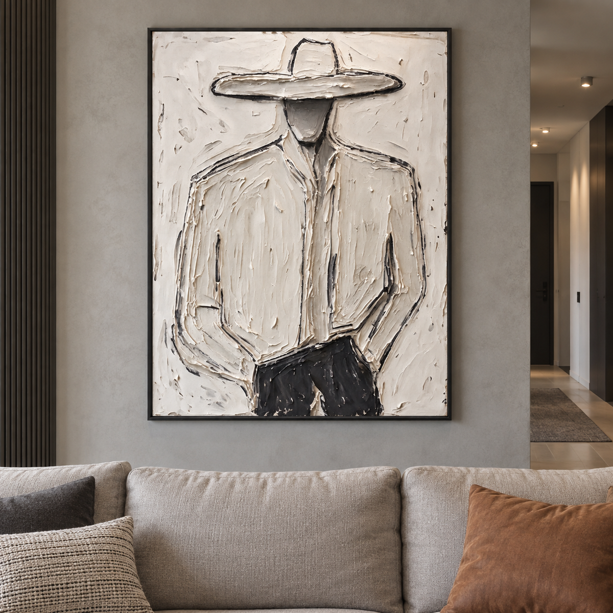A faceless cowboy in a pale wide-brimmed hat and light shirt with dark trousers against an off-white background, shown in a industrial living room.