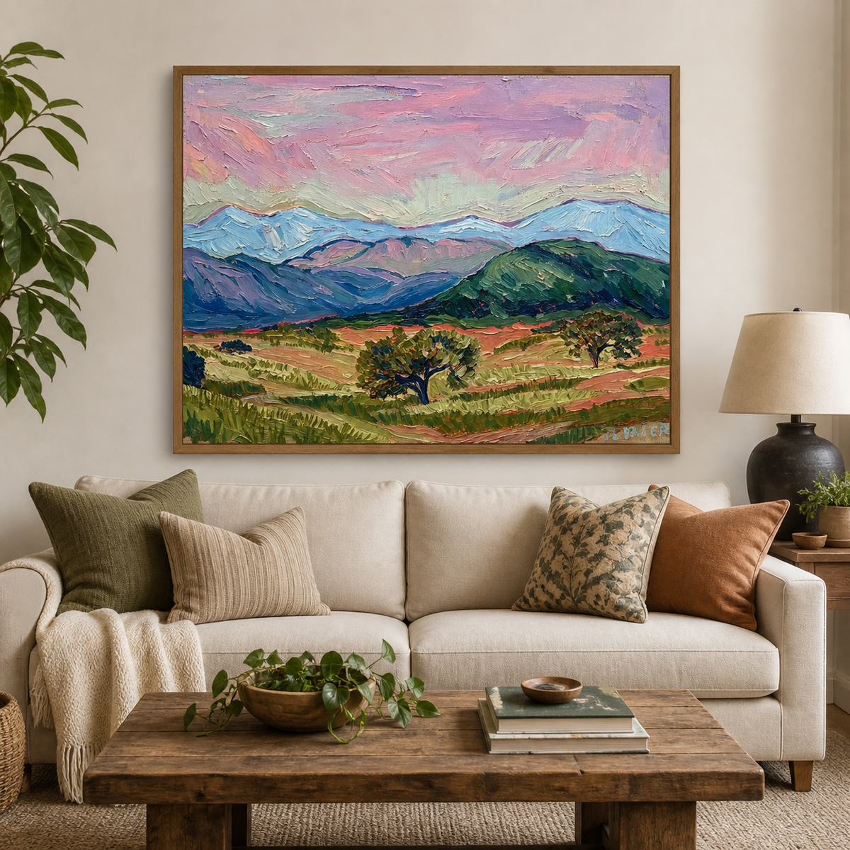 Colorful mountain landscape wall art with a pink sky, blue peaks and green valley displayed above a neutral sofa.