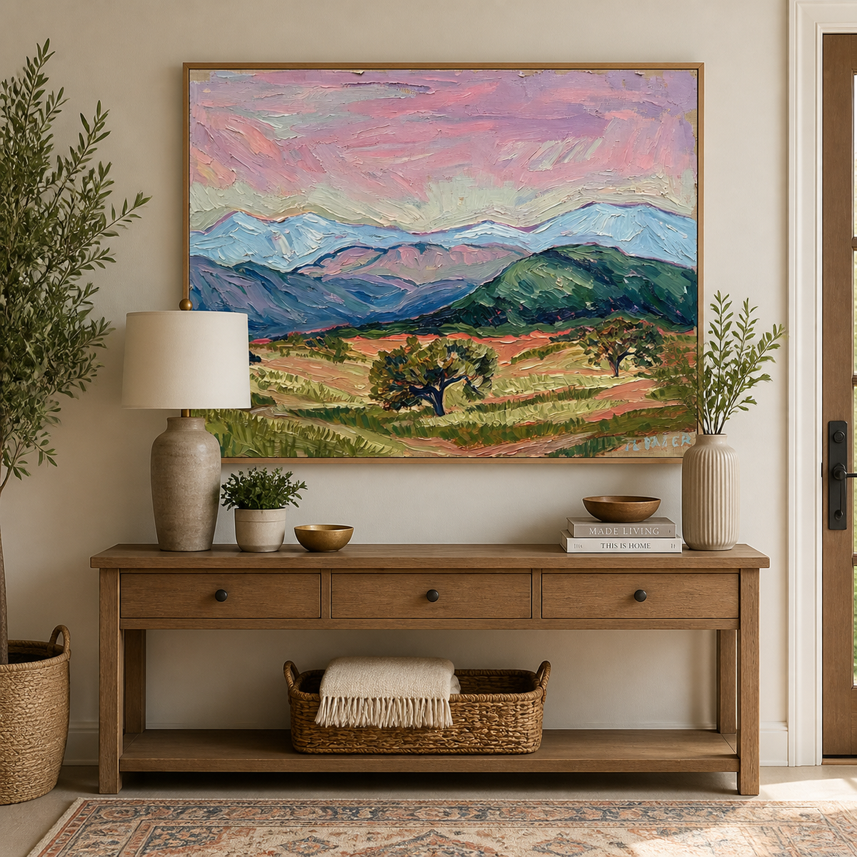 Colorful mountain landscape wall art with a pink sky, blue peaks and green valley displayed above a neutral sofa.