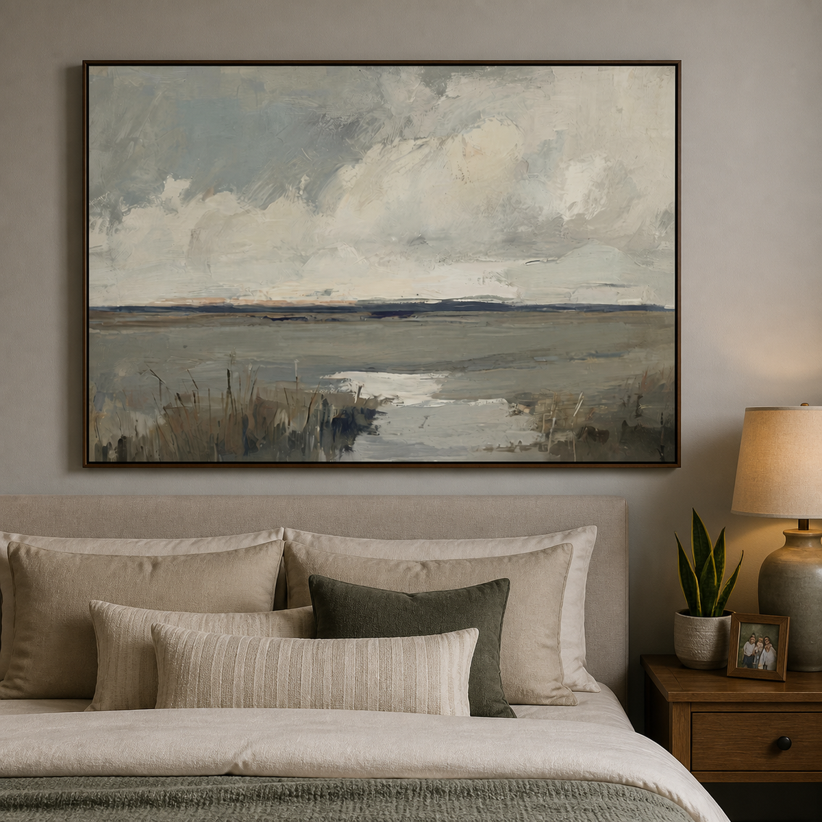 Neutral coastal wall art with a tidal marsh, cloudy sky and gray-blue textured shoreline displayed above a wooden dining table.