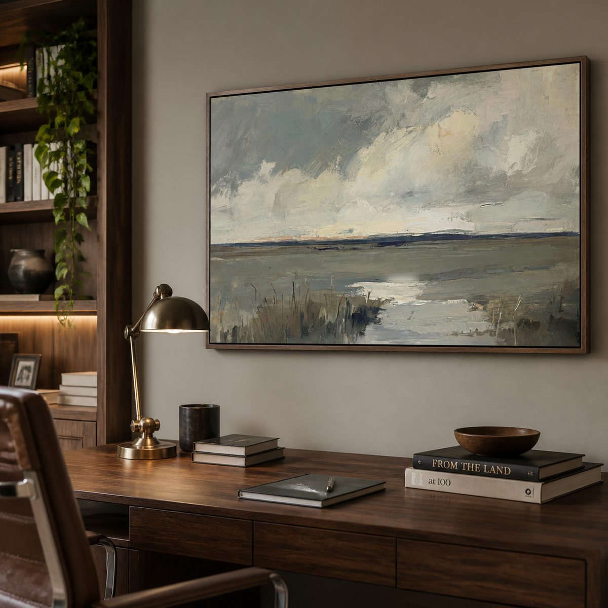 Neutral coastal wall art with a tidal marsh, cloudy sky and gray-blue textured shoreline displayed above a wooden dining table.