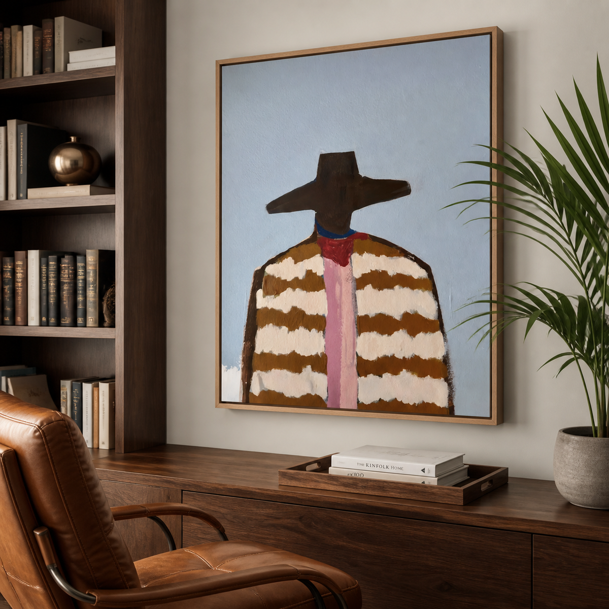 Western cowboy portrait with a wide brown hat, striped jacket and pink necktie displayed above a neutral sofa.