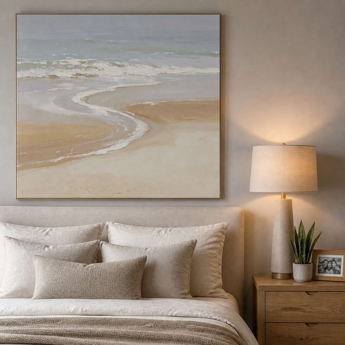 Square neutral coastal wall art with soft blue-gray ocean waves and a curved beige shoreline displayed above a wooden dining table.
