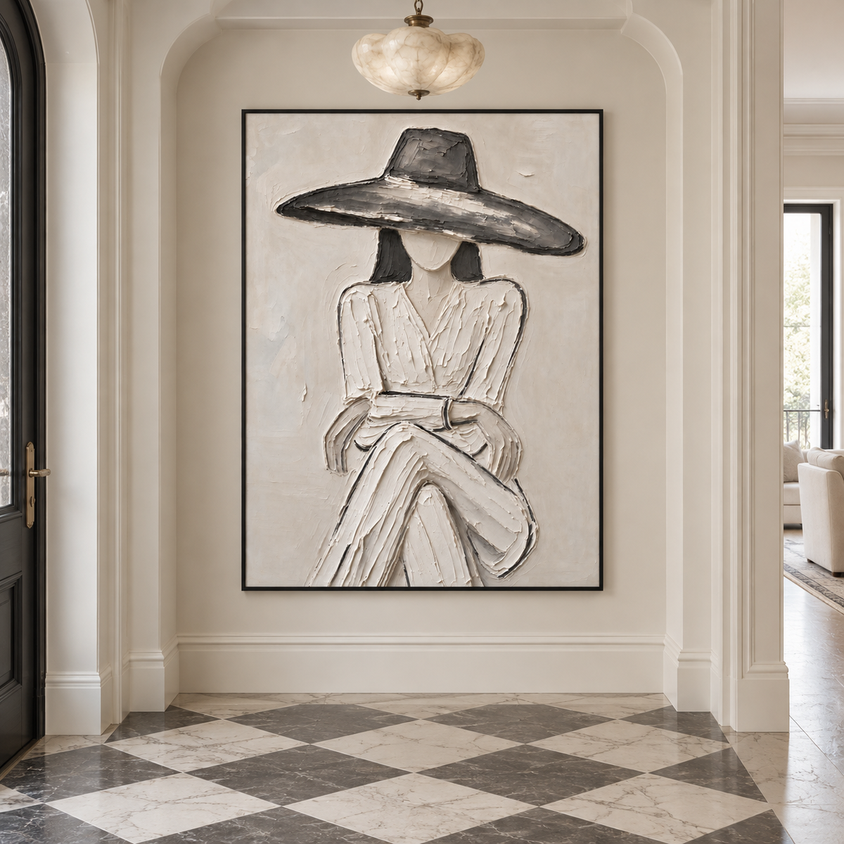 A seated woman in a pale dress and broad charcoal hat with folded hands against an off-white background, shown in a french modern entryway.