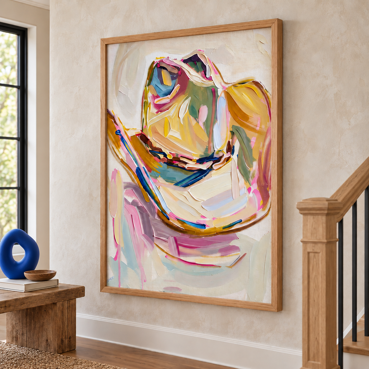 A single cowboy hat with a curled brim and a dark hatband depicted in broad pink, yellow, blue, green and cream strokes on a pale background, shown in room setting 5.