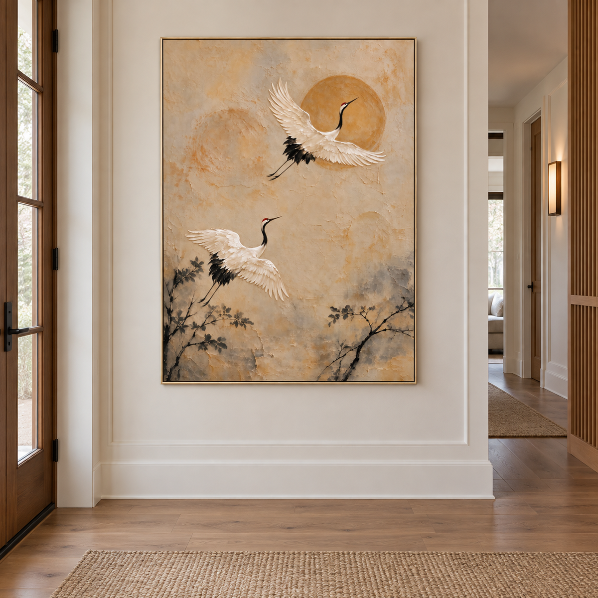 Two white cranes rising past an ochre sun above dark branches on a warm beige background, shown in a japanese inspired entryway.
