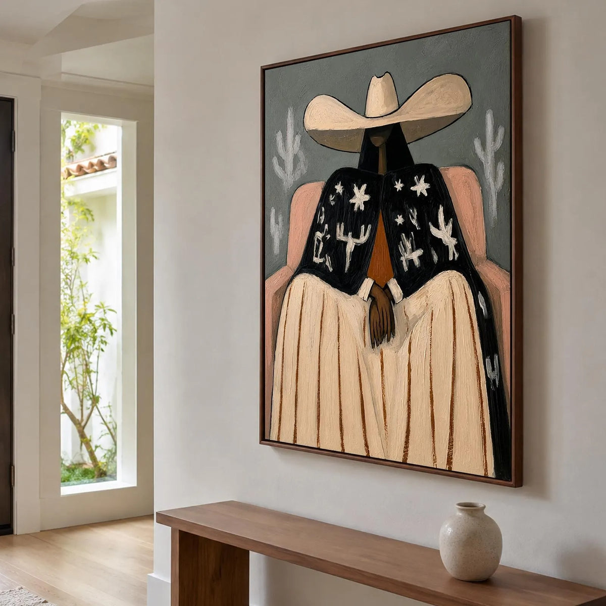 A seated cowgirl in a broad cream hat, pale skirt and black jacket patterned with white desert motifs against a gray background, shown in room setting 5.