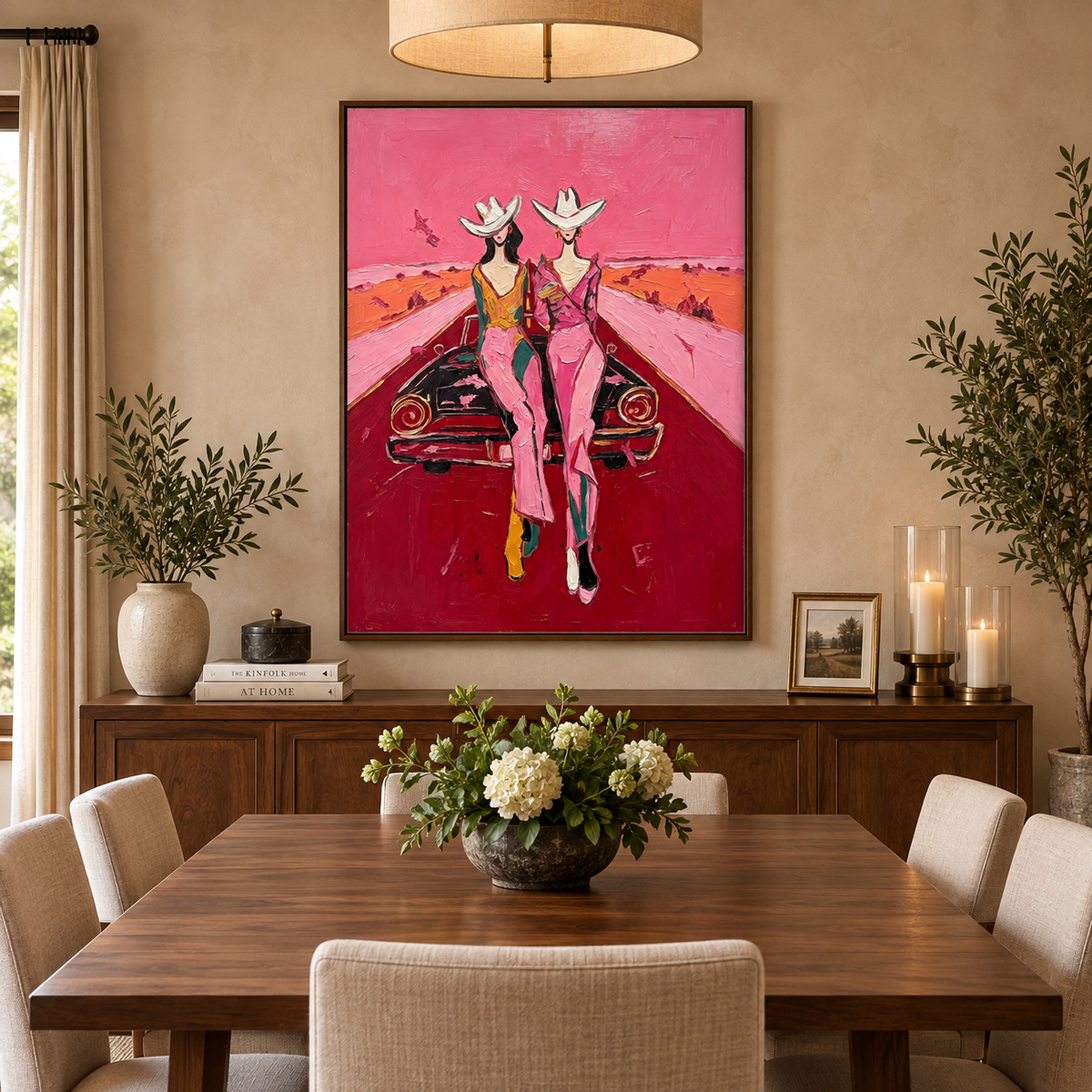 Two cowgirls in white hats and pink trousers beside a dark vintage car on a red desert road, in a dining room.