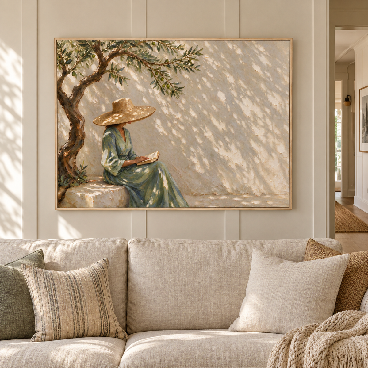 A woman in a straw hat and green dress holding an open book beneath a twisting tree with dappled sunlight on a pale wall, shown in a relaxed living room.