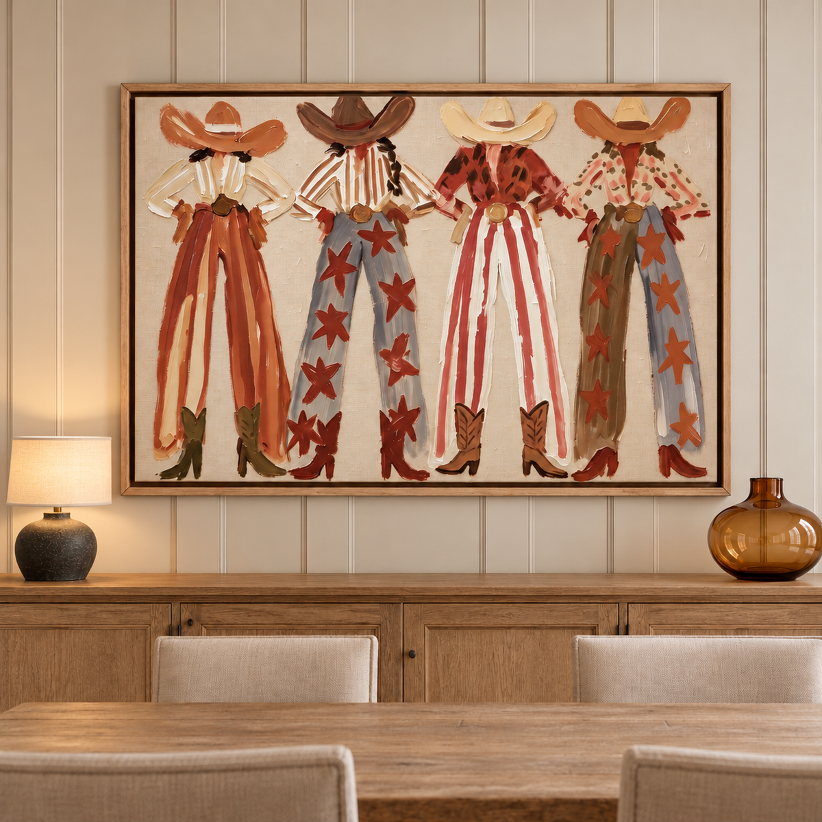 Four faceless cowgirls standing with hands on hips in broad hats, patterned shirts, striped and star-covered wide-leg pants and cowboy boots against a cream background, shown in room setting 2.