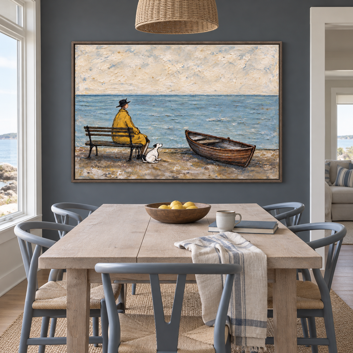A man in a yellow coat seated on a bench looking out over blue water with a small white dog beside him and an empty wooden rowboat on the beach, shown in room setting 2.