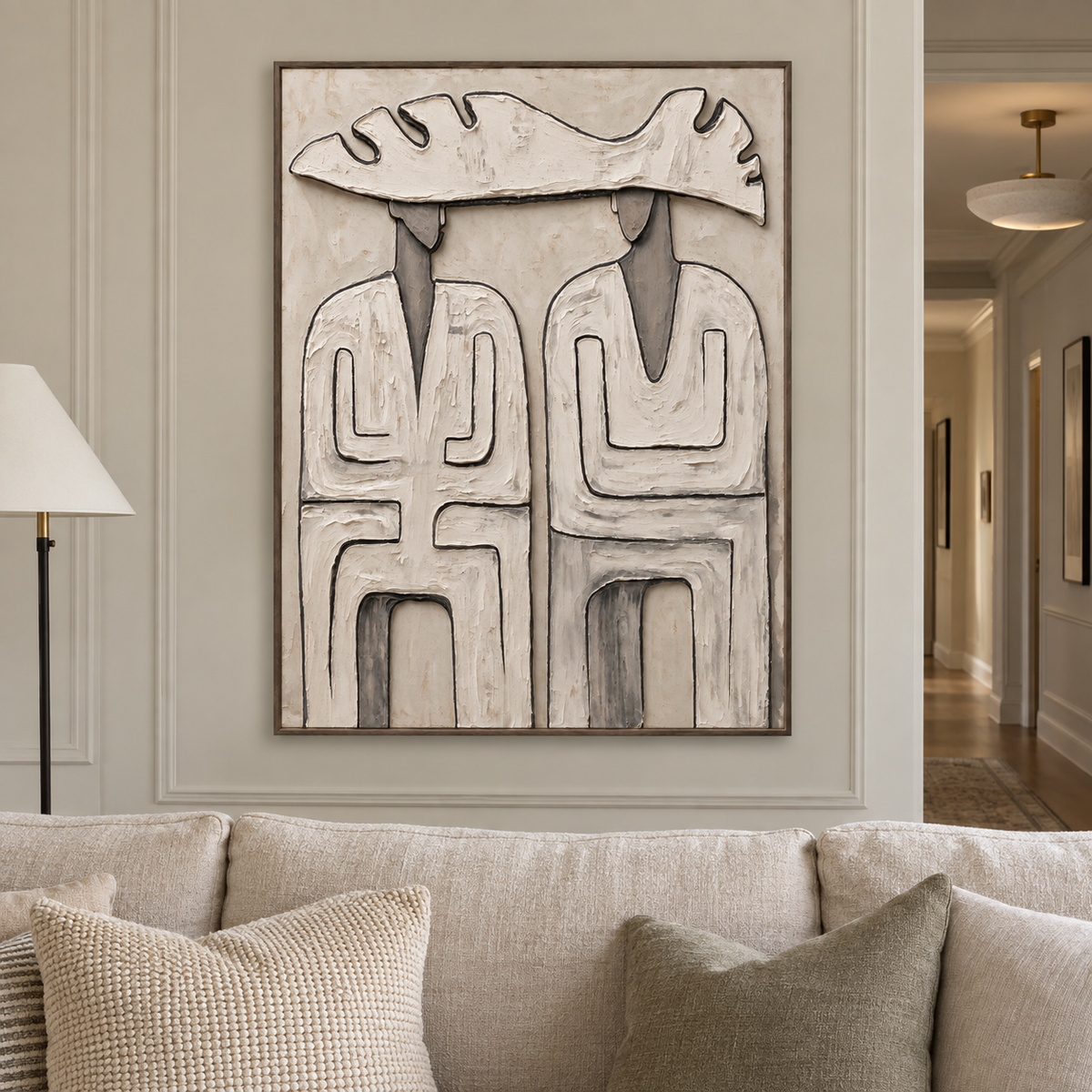 Two abstract figures beneath a single wide pale hat with dark geometric outlines on a warm neutral background, shown in a modern living room.